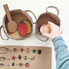 a child is playing with an apple and headphones made out of cardboard boxes on a table