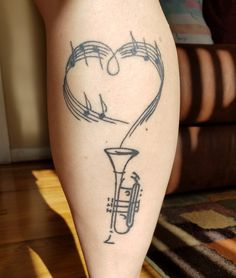 a tattoo on the leg of a woman with musical notes and a trumpet in her heart