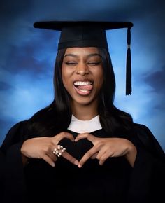 a woman wearing a graduation cap and gown making a heart with her hands