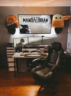 a computer desk topped with a black chair and two cartoon heads on the wall above it