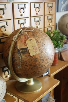 an old globe sits on top of a wooden table in front of many filing cabinets