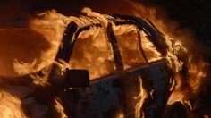 a burned car is shown in the dark with flames coming out of it's windows