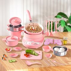 a pink kitchen set with utensils and other items on a wooden table top