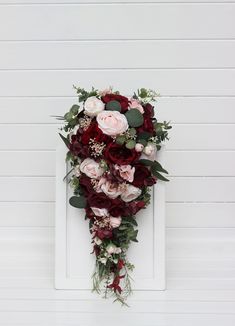 a bouquet of flowers hanging on the side of a white door with red and pink flowers