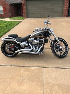 a motorcycle is parked in front of a house on the driveway with no one around it