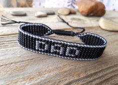 a black and white beaded bracelet sitting on top of a wooden table next to rocks