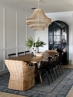 a dining room table with wicker chairs and a chandelier hanging from the ceiling