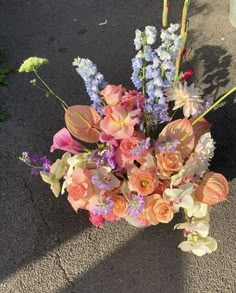 a vase filled with lots of flowers on top of a cement floor next to a sidewalk