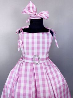 a pink and white checkered dress with a bow on the back