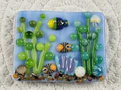 a glass plate with various sea animals and plants in it on a white carpeted surface