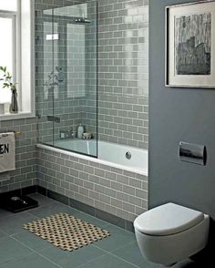 a white toilet sitting next to a bath tub in a bathroom with gray walls and floor