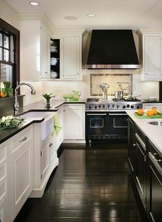 a kitchen with white cabinets, black counters and stainless steel stove top oven in the center