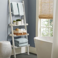 a bathroom with a ladder shelf next to a bathtub and toilet in it,