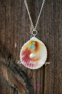 a necklace with a shell and pearls hanging from it