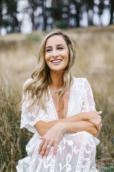 a woman is sitting in the grass and smiling