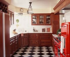 a kitchen with black and white checkered flooring, red refrigerator freezer and cabinets