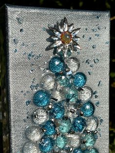 a small christmas tree made out of glass beads and silver balls with a sunburst on top