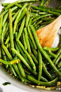 green beans in a white bowl with a wooden spoon