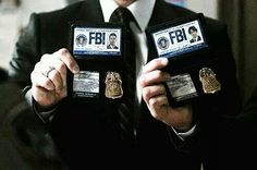 two men in suits holding up their badges