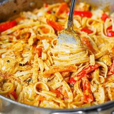 a fork is stuck into some pasta with sauce and peppers on it in a skillet