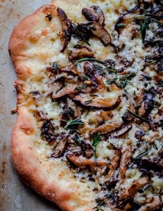 a close up of a pizza on a pan with mushrooms and herbs toppings in it