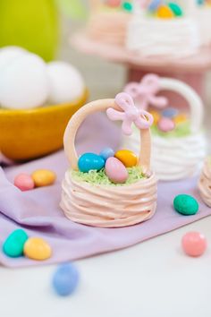 a small basket filled with eggs and candy on top of a table next to other desserts