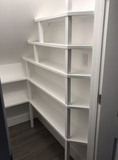 an empty white bookcase in the corner of a room