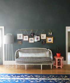 a living room with green walls and pictures on the wall above the couch, along with a blue rug