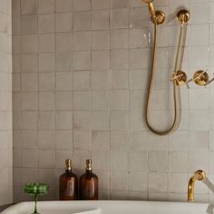 a bathroom with a tub, shower head and soap dispenser