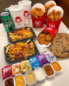 several trays of food on a table with drinks, cookies and other condiments