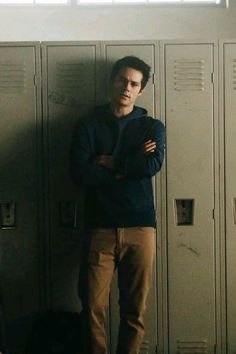 a man standing in front of lockers with his arms crossed