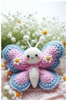 a crocheted butterfly sitting on top of a doily with daisies in the background