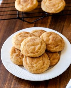 a white plate topped with cookies on top of a wooden table next to a cooling rack