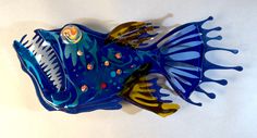 a blue and yellow fish shaped dish on a white surface