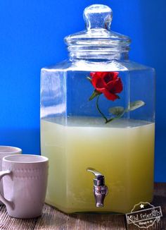 a glass jar filled with liquid and a red rose floating in it, on top of a wooden table