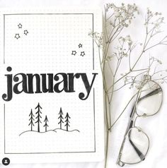 a notebook with the word january written on it next to some flowers and reading glasses