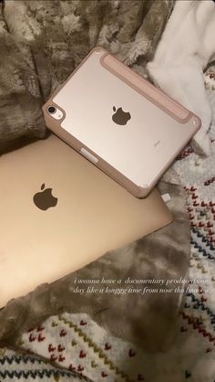 two apple ipads sitting on top of a bed next to each other, one gold and the other silver