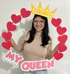 a woman wearing glasses and a crown holding up cut out hearts