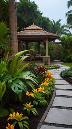 an outdoor gazebo surrounded by tropical plants and flowers in the foreground is a stone path that leads to a pavilion