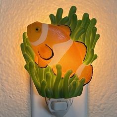 an orange and white clown fish light is on the wall next to some green plants