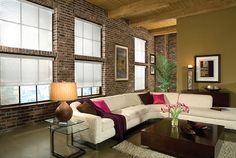 a living room filled with furniture and windows covered in shades of brown, white and pink