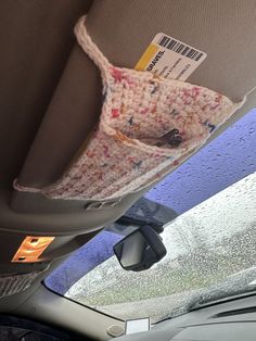 the interior of a car with raindrops on the windshield and an item in the passenger seat