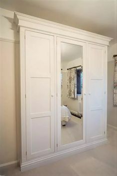 a large white closet with mirrored doors in the middle and curtains on the other side