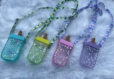 three water bottles with lanyards are laying on a furry surface