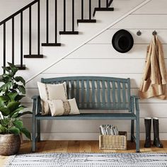 a bench sitting under a stair case next to a potted plant and bookshelf