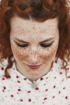 a woman with freckles on her face looking down