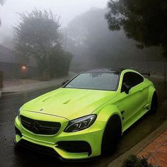 a bright yellow car is parked on the side of the road in front of some trees