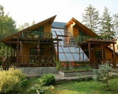 a large wooden house sitting on top of a lush green field next to tall trees