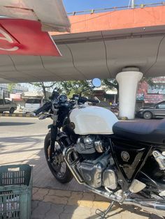 a black and white motorcycle parked under a gas station