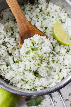 rice and limes in a pot with a wooden spoon